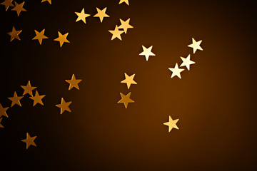 Trendy gold stars confetti falling on dark brown gradient background.
