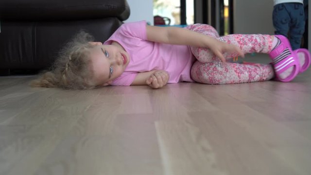 Playful girl romp on floor. Happy child have fun at home. Gimbal motion shot