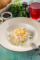 Russian traditional salad Olivier with egg yolk and glass of red drink on blue wooden table