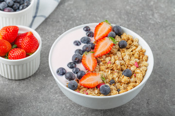 Granola with yogurt fresh strawberries and blueberries on a stone table. Healthy snack. The food for Breakfast. 