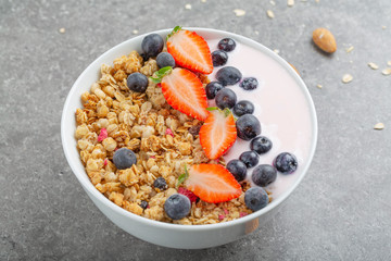 Granola with yogurt fresh strawberries and blueberries on a stone table. Healthy snack. The food for Breakfast. 