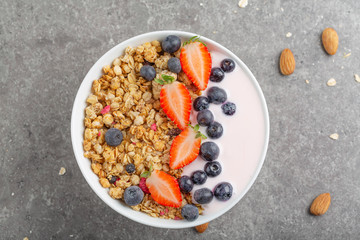 Granola with yogurt fresh strawberries and blueberries on a stone table. Healthy snack. The food for Breakfast. Top view.