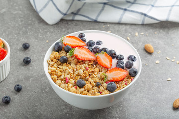 Granola with yogurt fresh strawberries and blueberries on a stone table. Healthy snack. The food for Breakfast. 