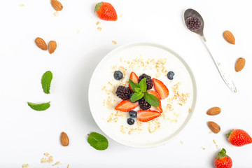 Greek yogurt with granola fresh strawberries, blueberries, blackberries and almonds on white table. Healthy snack. Breakfast food. Top view, copy space.