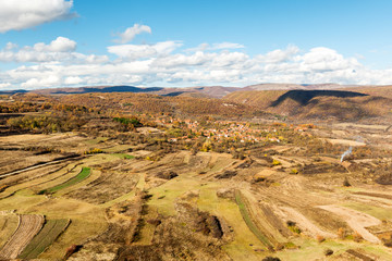 Beautiful aerial panorama of autumn rural scenery with old village, fields, hills and country roads