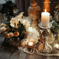 Luxury table decoration with pearls, flowers and burning candle in a silver candlestick.