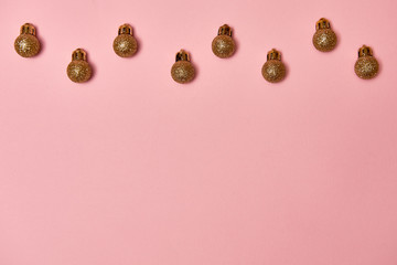Creative Christmas pattern with golden shiny baubles on pastel pink background, copy space. Minimal, winter, new year concept. Top view, flat lay