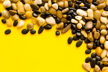 Summer trip to sea concept. Stones on yellow background top-down frame copy space