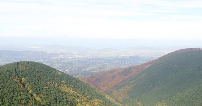 Hills and mountains on the horizon of beautiful nature with city in the forest valley view into vast distance of the Beskids Area during a windy sunny day captured in Radhost Pustevny area 4k 60fps.
