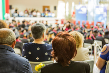 an audience of friends and family at university. the audience watches a celebration in a hall.