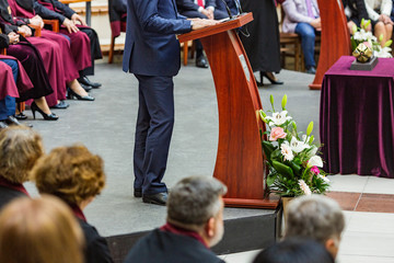 student speaks in front of colleagues and professors dressed in robes and formal costumes. lecture in front of students. speaking in front of a crowd of people.