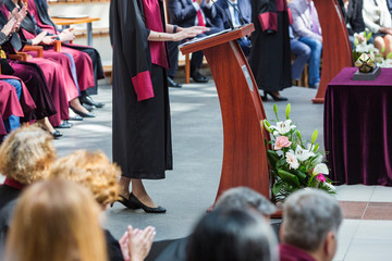 student speaks in front of colleagues and professors dressed in robes and formal costumes. lecture in front of students. speaking in front of a crowd of people.