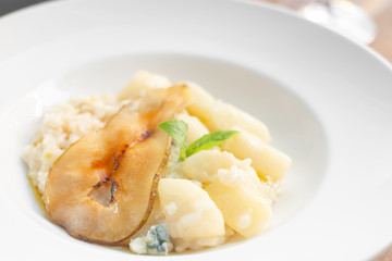 Risotto with pear and Gorgonzola on a white plate. Italian dishes are served in the restaurant