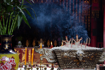 The smoke of incense sticks and candles on a shrine in Bangkok, Thailand.