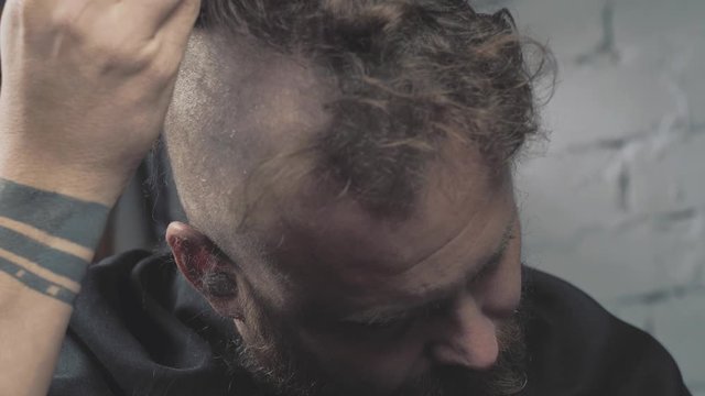 a man with a beard shaves his head with an electric trimmer. bearded punk hipster shaves his mohawk. 4k video. slow motion. 23.98 fps