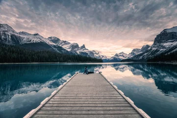 Fotobehang Grijs Traveler relaxing on wooden pier in Maligne lake at Spirit island, Jasper national park  © Mumemories