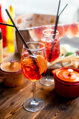 Glass of cold aperol spritz cocktail with Spanish snacks on wooden background.