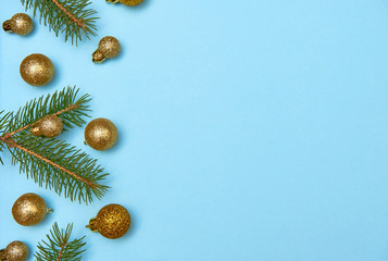 Creative Christmas pattern with golden shiny baubles and fir tree branches on pastel blue background, copy space. Minimal, winter, new year concept. Top view, flat lay