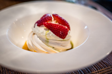 Pavlova with vanilla cream and fresh strawberry and passion fruit coulis