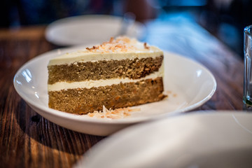 Homemade carrot cake with cream cheese and toasted coconut in a white bowl
