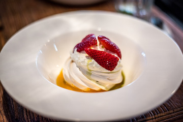Pavlova with vanilla cream and fresh strawberry and passion fruit coulis