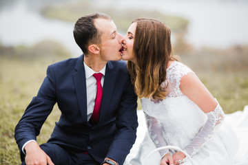 Beautiful bride and groom embracing and kissing on their wedding day outdoors