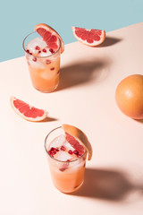 Fresh summer cocktail with pink grapefruit slices. Divided blue and beige bankground. Abstract conception.