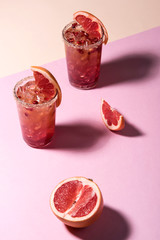 Fresh summer cocktail with pink grapefruit slices. Divided pink and beige bankground. Abstract conception.