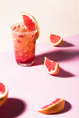 Fresh summer cocktail with pink grapefruit slices. Divided pink and beige bankground. Abstract conception.