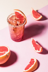 Fresh summer cocktail with pink grapefruit slices. Divided pink and beige bankground. Abstract conception.