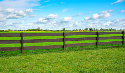 Fototapeta na wymiar Green fence field and a blue sky. Pastures out of town.
