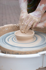 Hands forming clay on the pottery wheel