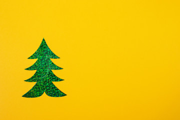 Christmas minimal mockup in yellow with one bright green holographic Christmas tree with copy space.