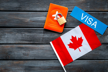 Visa to Canada concept. Canadian flag near passport and lock on dark wooden background top view copy space