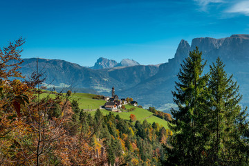 Fototapeta na wymiar Panoramic view of the village and Nikolaus church of Mittelberg with the Langkofel, Plattkofel and Rosengarten mountains in the background