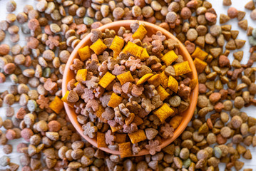 Top view of natural pet food in a clay bowl on white table