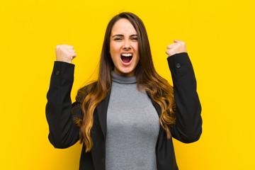 young pretty woman shouting aggressively with an angry expression or with fists clenched...