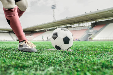 On a football field, a player kicks the ball with his left foot.