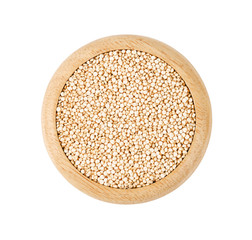 Raw white quinoa seeds in wooden dish.