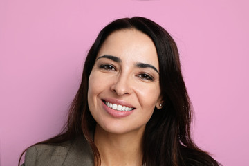 Fototapeta premium Portrait of young and beautiful woman smiling and posing on the pink background. Isolated.