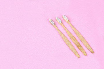 Bamboo toothbrushes on pink background.