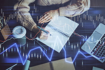 Forex graph on hand taking notes background. Concept of research. Double exposure