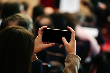 A woman takes a picture with a mobile phone in a meeting
