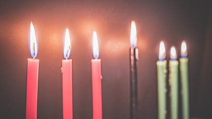 Kwanzaa holiday concept with decorate seven candles red, black and green, gift box, pumpkin,corn and fruit on wooden desk and background.