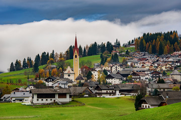 Fototapeta na wymiar Alpine mountain village in Welsberg Taisten region in Italy during cloudy autumn evening.