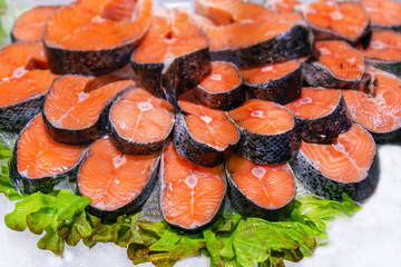 Salmon red fish steak at market. Raw fresh salmon steak as pattern background, close up. Large pile of fish meat with ice texture. Big organic heap of seafood farm salmon fish lined up for sale