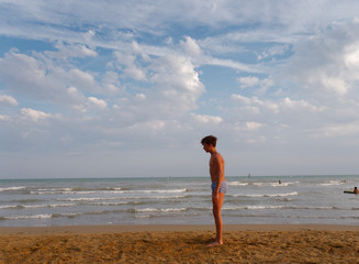 athletic teenager on the beach in jump on the background of the sea and sky