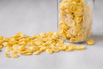 Corn flakes in a glass jar on white wooden surface. Place for your text