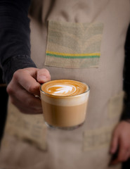 Barista makes latte coffee with milk in cafe closeup