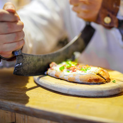 Traditional bread with sour cream and ham on German Christmas market. Closeup of fresh baked pretzel and hands of man on Xmas fair in Germany